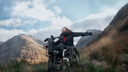 a woman with a handcycle on a mountain path