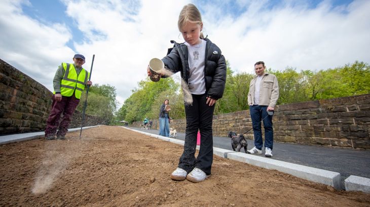 child scatters seeds on the Padiham Greenway