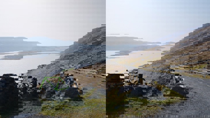Bike leaning up against rock by road overlooking sea inlet