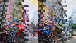 Two people sat at table on table outside old fashioned train station waiting room with bikes in the foreground