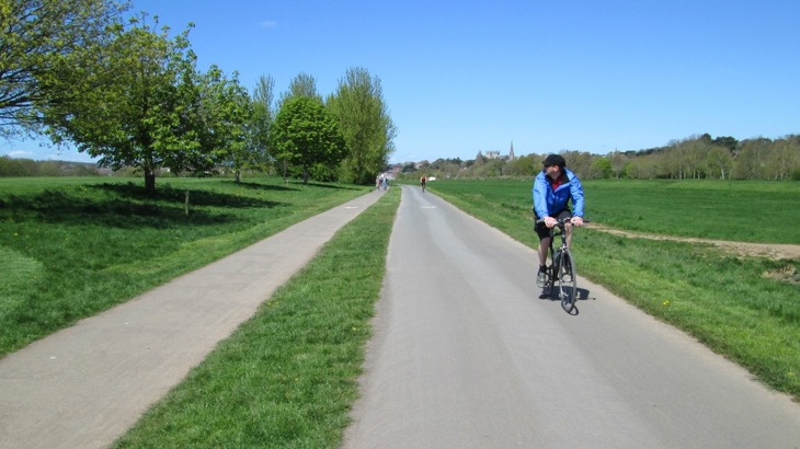 A person cycles along a traffic-free path surrounded by grass