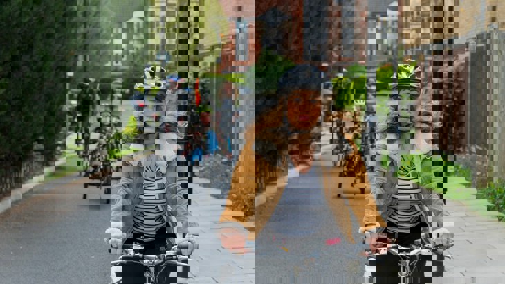 A woman rides a bike on a traffic-free path with an adapted bicycle following in the background 