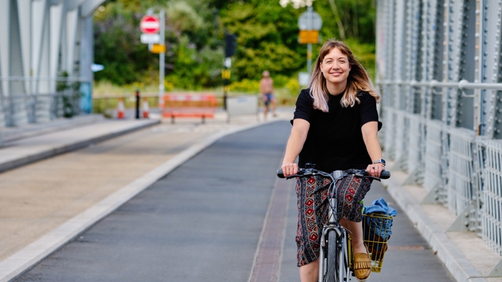 Girl cycling towards the camera along bridge