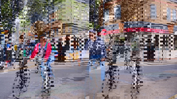 A lady and a man cycle casually through a London borough