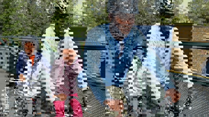 A man and two young girls riding a tandem bike over a bridge