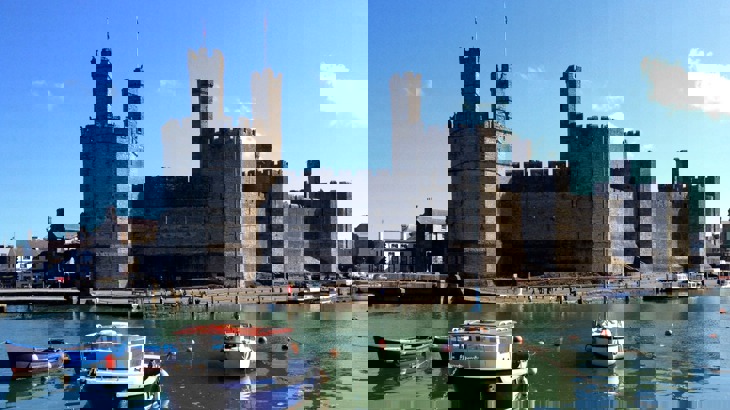 A medieval castle looking over a harbour with boats