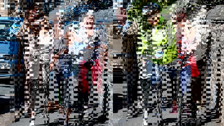 A group of people walking down the street together chatting and laughing