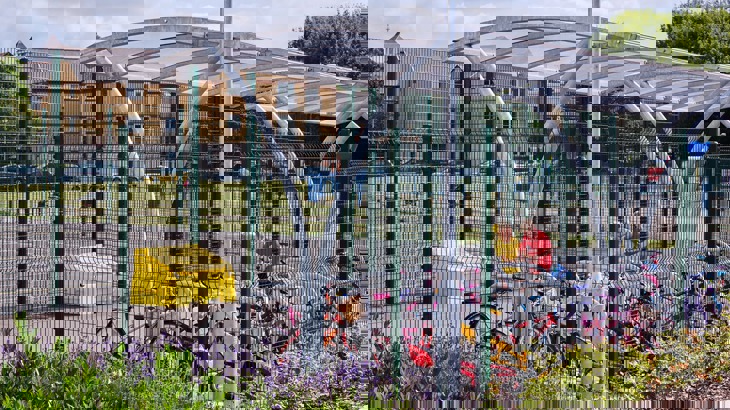 Secure cycle storage in school playground with two children locking up their bikes