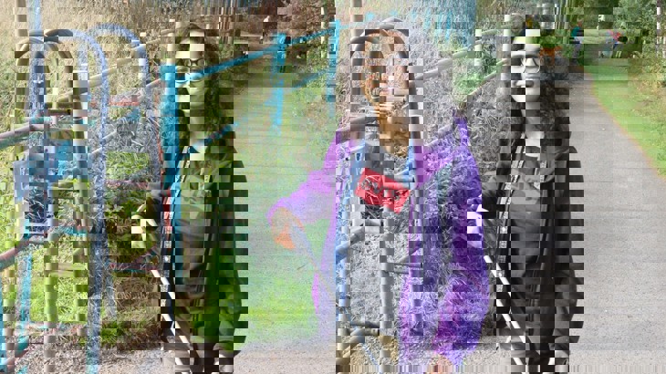 A girl smiling on a traffic-free route using a litter picker to collect rubbish and clear the route.