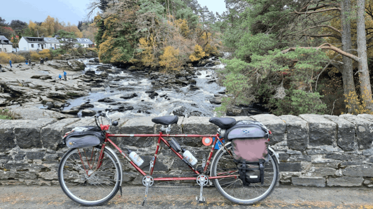 A tandem bike sits on a bridge overlooking a beautiful river
