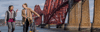 two people walk and cycle past the Forth Road Bridge between Edinburgh and Fife