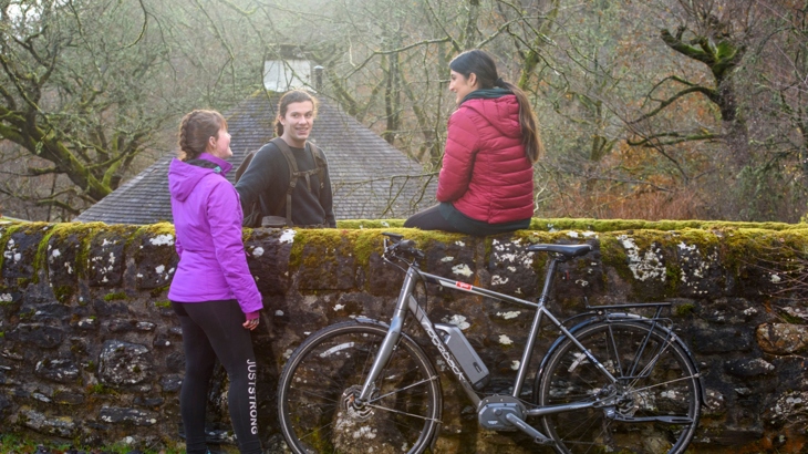 Group of young people outside in winter sitting on wall with an ebike
