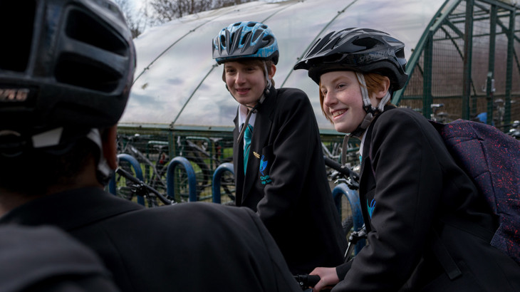 Two high school boys wearing helmets talking to their friend.