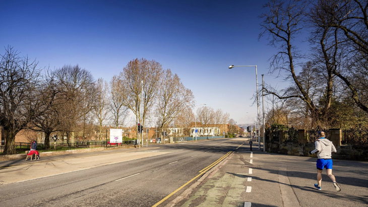 Lone jogger and dog walker on either side of empty road in Belfast, March 2020 Covid lockdown