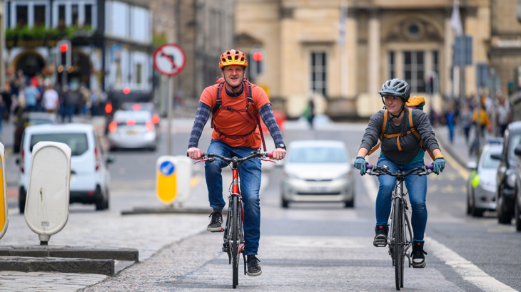 Two people cycling together in a city
