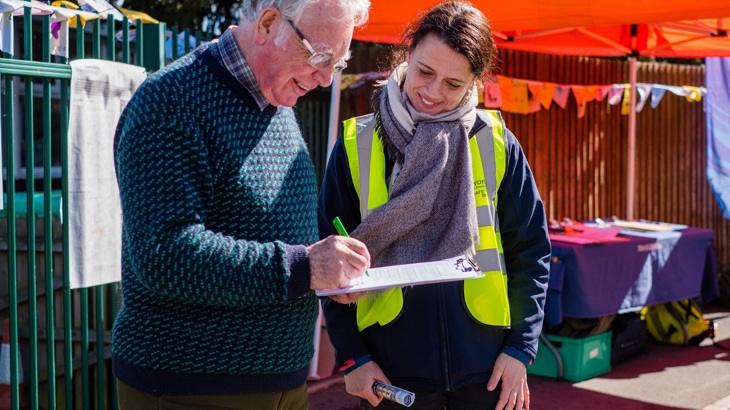 A resident holding a clip board gives views to a Walk Wheel Cycle Trust team member on street design during a community engagement event.
