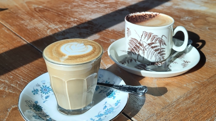 Two mugs of coffee on chinaware on a wooden table.