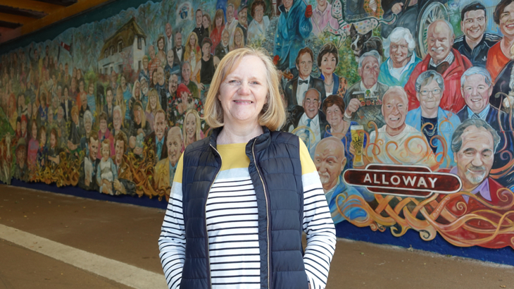 Shelagh, Trustee at Alloway Tunnel Project, standing in front of the art mural.