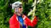 A person in exercise clothes, helmet and sunglasses looking at elderflowers
