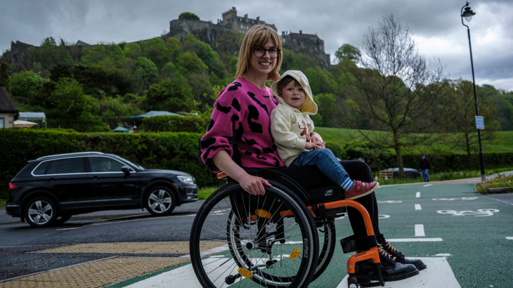 Mum in a wheelchair with young son / toddler, on zebra crossing across cycleway