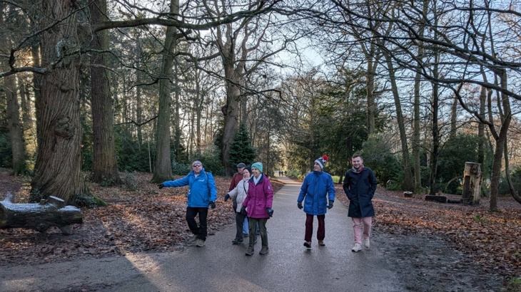 A group of people walk in a frosty woodland