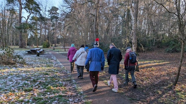 A group of people walk in a frosty woodland