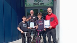 Walk Wheel Cycle Trust staff member stands posing for a photo with staff and pupils from Maes Derw pupil referral unit after they achieved their Silver Active Travel School Award.
