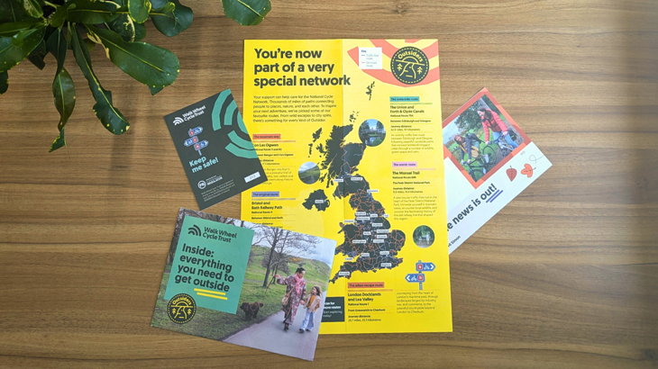 Outsiders regular givers welcome pack laid out on a table: it features a poster map of the National Cycle Nerwork, important information, and tips and advice for making the most of the Network.
