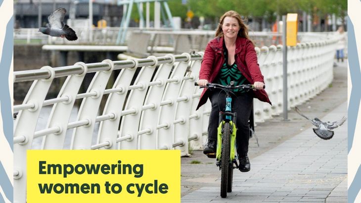 Woman cycling along riverside path in Limerick city, Ireland