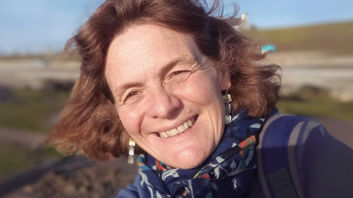 Land Manager Liz Edwards smiles at the camera, out on the Network with blue skies behind her.