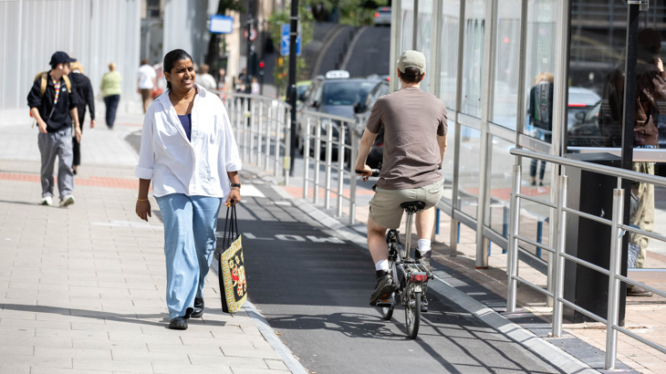 A lively street with a segregated cycle, a bus stop and people walking