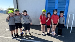 Smiling pupils from Ysgol Pentreuchaf pose for a photo with their bike hlemets on.