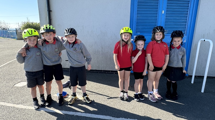 Smiling pupils from Ysgol Pentreuchaf pose for a photo with their bike hlemets on.