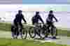 Three people cycling along the shore line on the Pier to Pier Way.