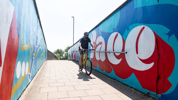 man cycling through a subway with mural