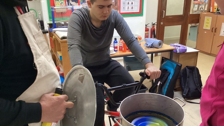 A pupil rides a stationary bike that has been specially designed to make art with paint.
