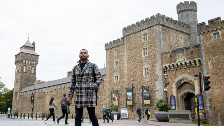 An adult walking on Castle Street in front of Cardiff Castle.