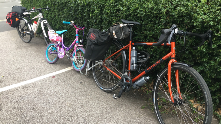 Two adult and one child bike in line, with panniers and water ready for an adventure.